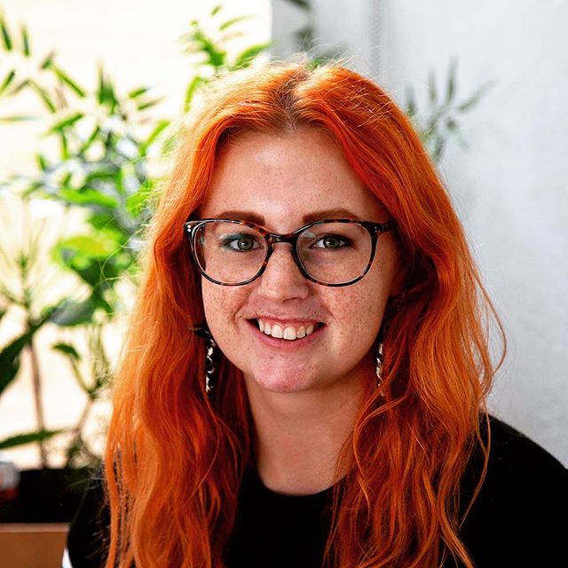 A headshot of a girl with ginger hair and glasses. 